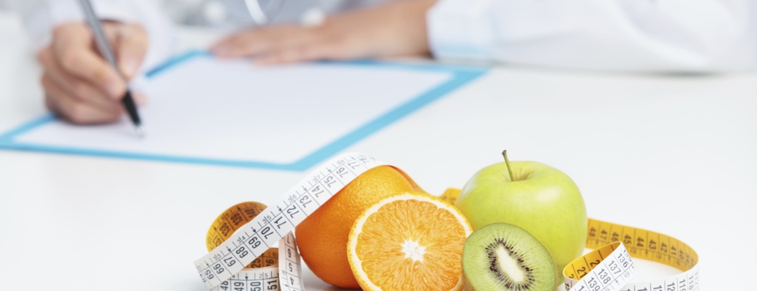 "Doktorun önünde masanın üstünde ölçüm bandı ile çevrili portakal, elma ve kivi bulunan bir görsel. Sağlıklı yemek yemek önemi ve ölçümün diyet üzerindeki rolünü temsil eder
